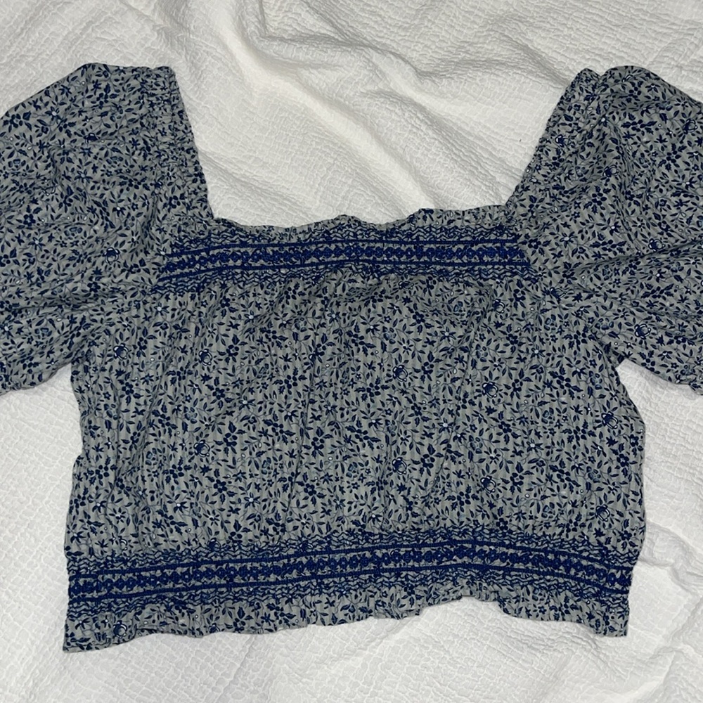 Blue smocked crop blouse with crew neck, cap sleeves, button back closure